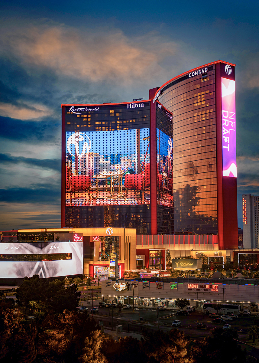 Resorts World Las Vegas exterior at dusk with illuminated hotel towers and a large LED facade display