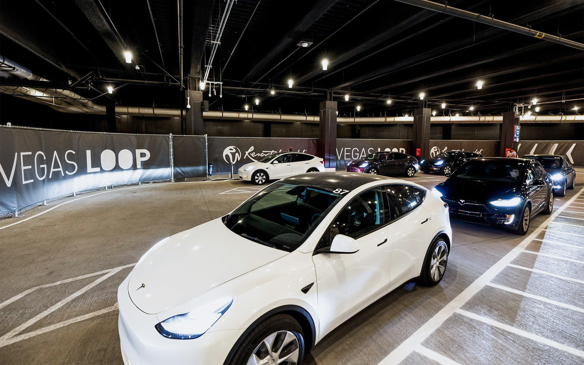 Tesla vehicles inside the Resorts World Las Vegas Vegas Loop station illuminated by Vela 6 cylinders