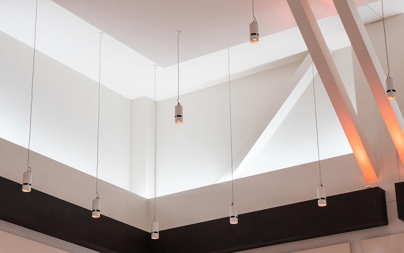 Atria cylinders suspended from a high ceiling with angular architectural beams at Resorts World Las Vegas