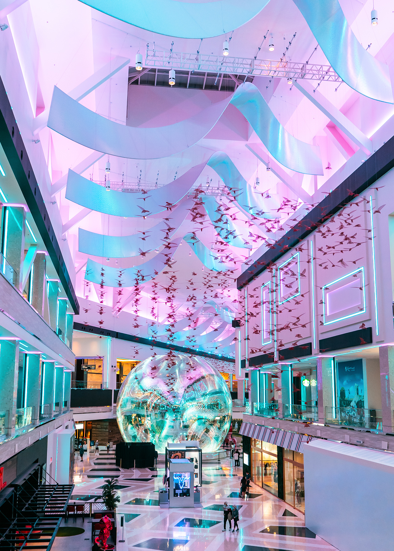 Wide view of The Globe in The District with teal and magenta architectural lighting throughout the atrium