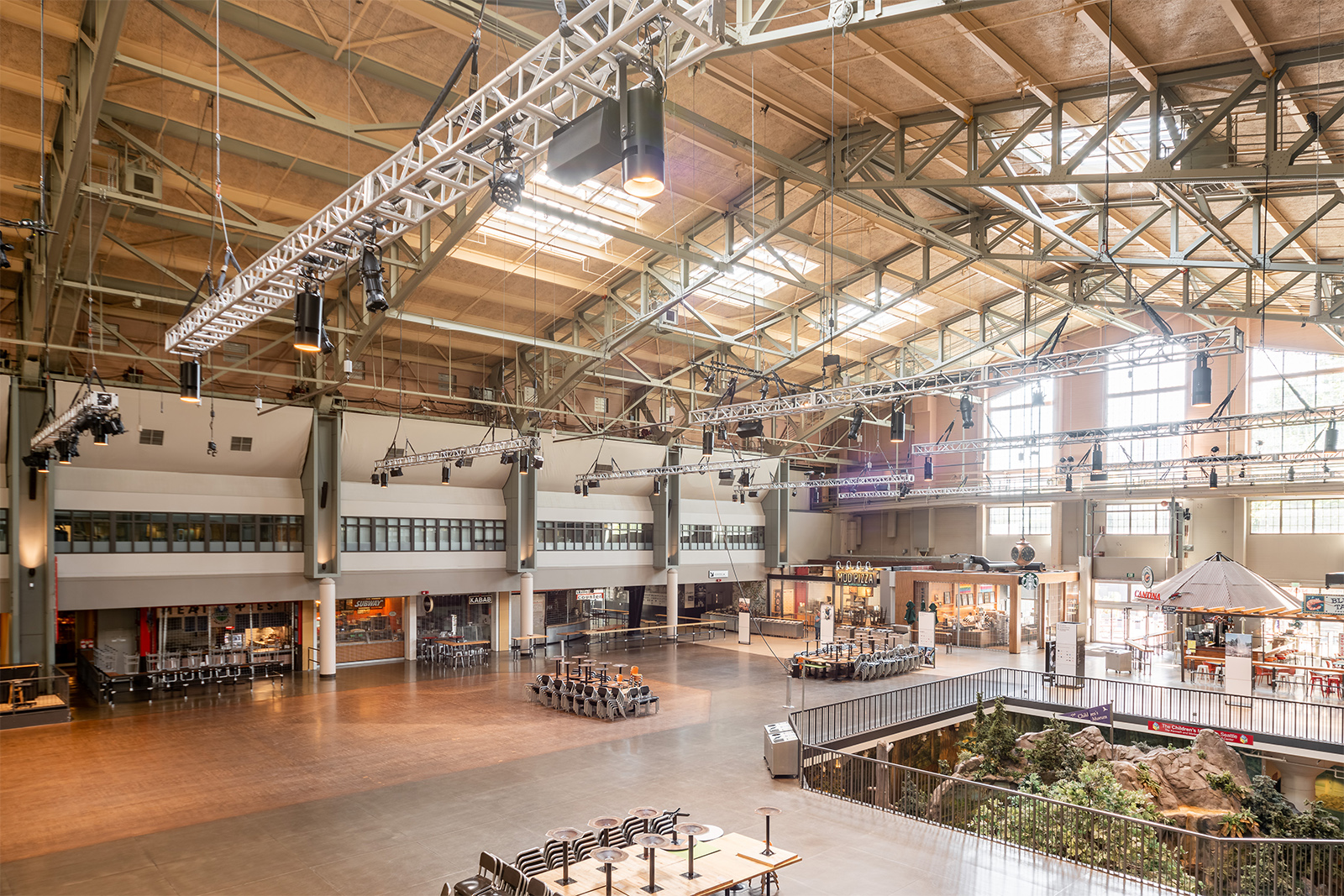 Interior of Seattle Center Armory with dining tables and a suspended lighting truss